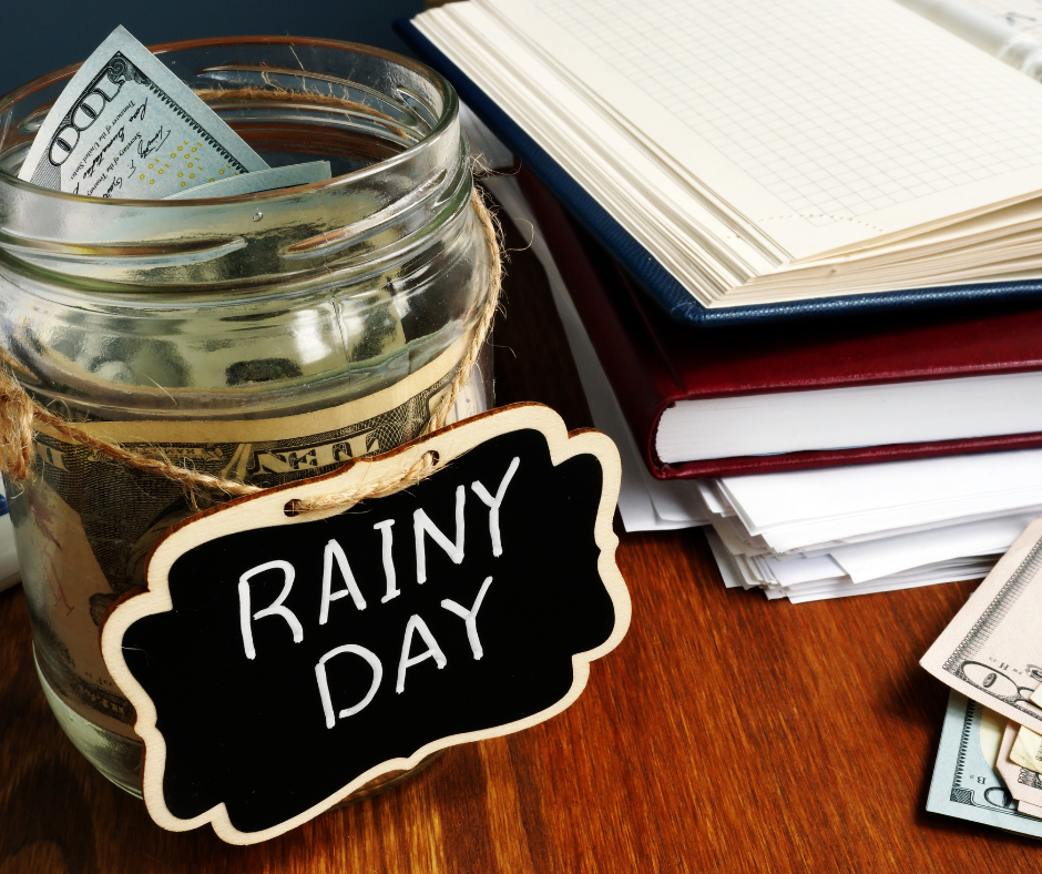 a picture of a jar with money inside of it and a sign on it writes Rainy Day and with notes book next to it