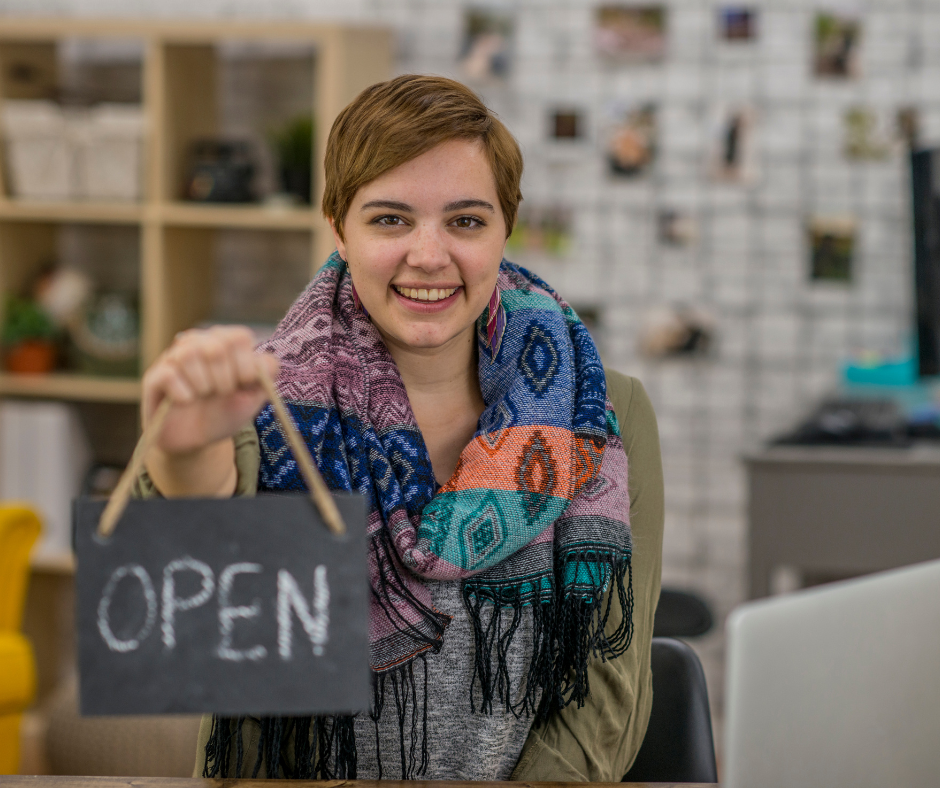 a woman with short hair holding an open sign