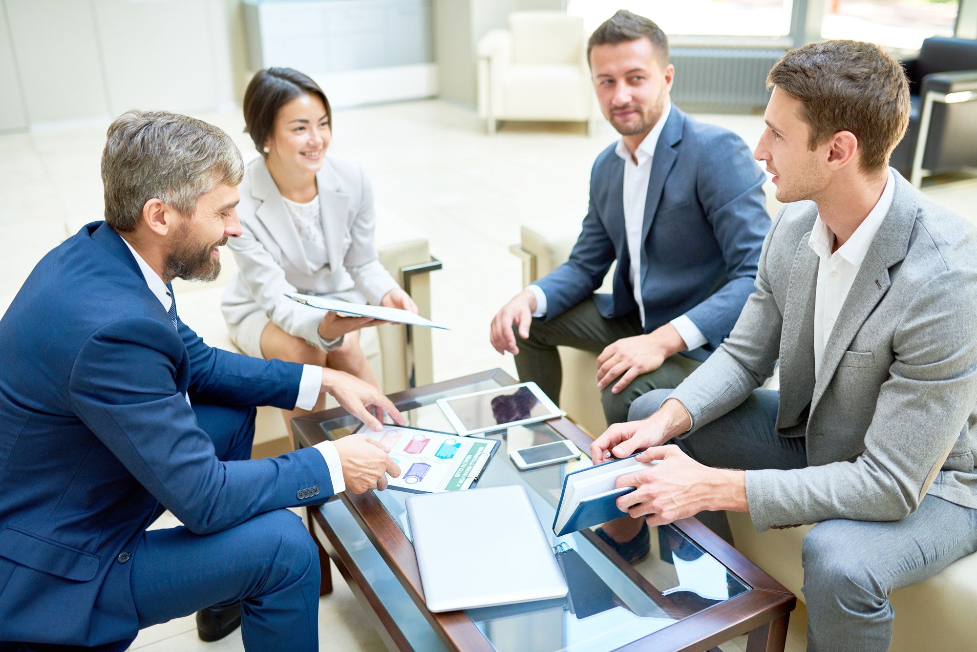 a group of people sitting in an office having a meeting sitting on the couch across from each other