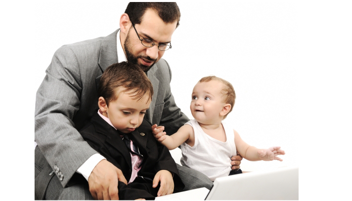 A man wearing a grey suit with a child and a baby sitting Infront of him looking at a laptop.